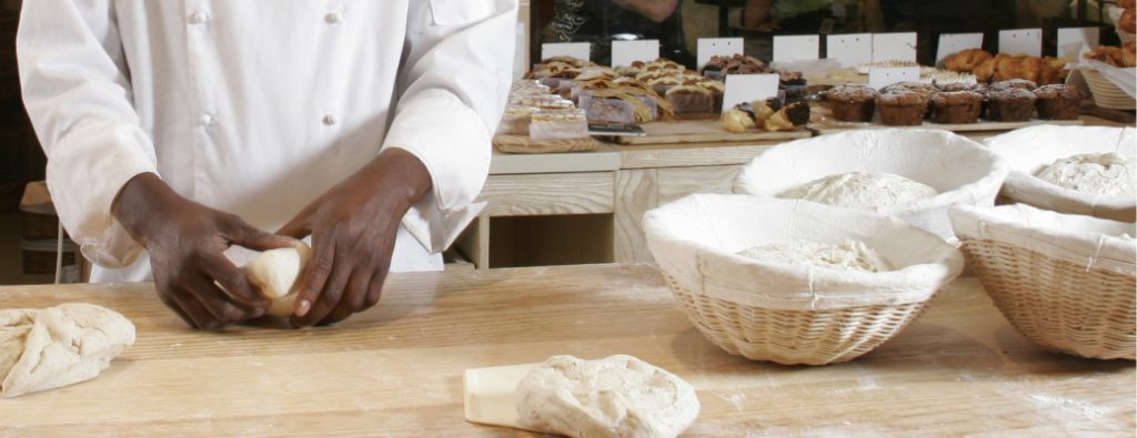 A baker shaping dough in a bakery
